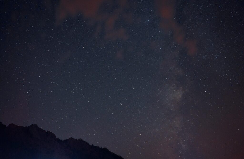 Vibrant night sky with stars and Milky Way over silhouetted mountains.